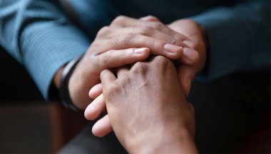 A couple sitting close hold hands