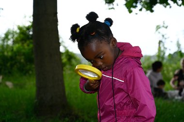 Little girl outside looking through a magnifying glass