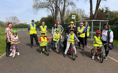 A group young children with their bikes and cycling instructors, wearing high-vis and helmets