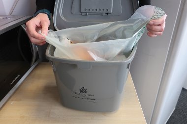 Someone tying up a food waste bag inside a Hillingdon caddy