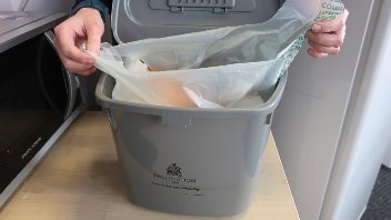 Someone tying up a food waste bag inside a Hillingdon caddy