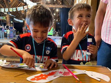 Two young boys smiling and laughing while crafting