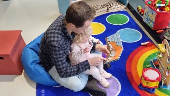 An adult man and little girl read a book at the bunker