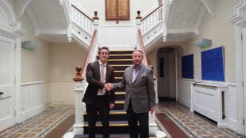 Cllr Jonathan Bianco and Keith Smith, CEO of HRUC, shake hands at the foot of the staircase of Barra Hall to mark the completed sale.